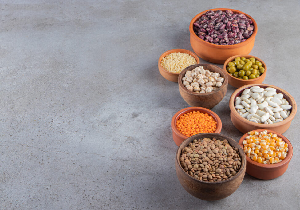 Clay bowls full of raw lentil, peas and beans on stone background. High quality photo