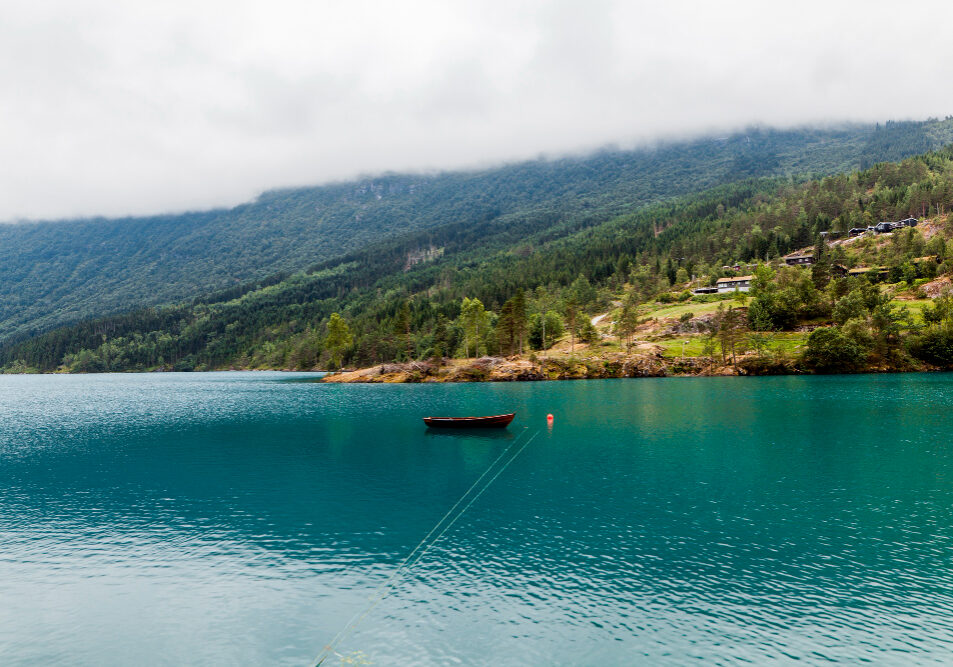 small-boat-moored-blue-calm-lake-with-green-mountain