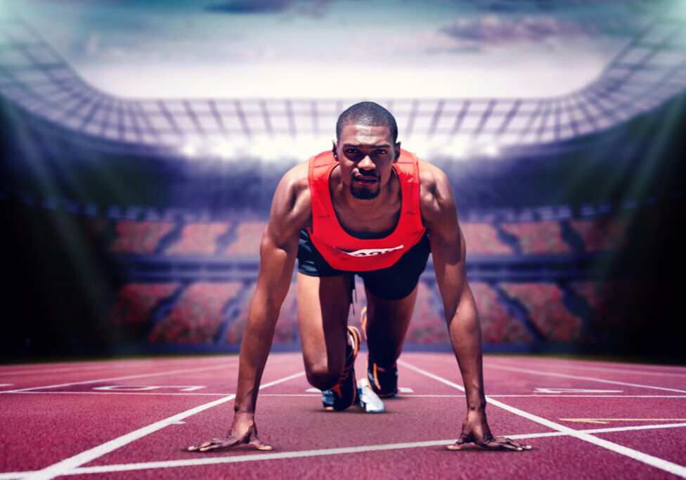 Composite image of athlete man in the starting block in a stadium