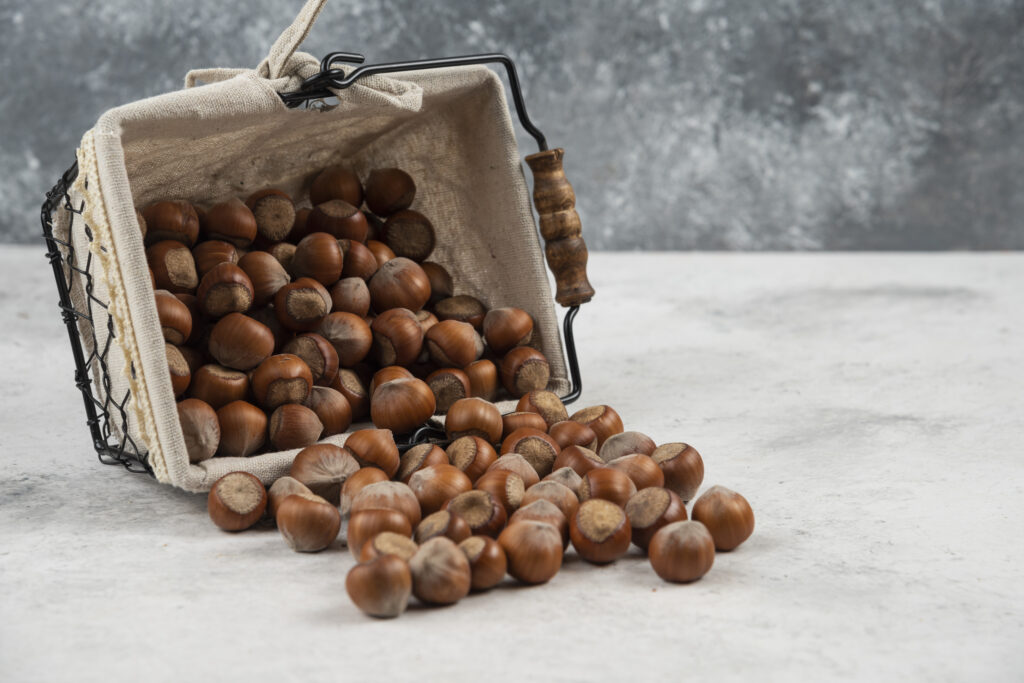 Pile of organic shelled hazelnuts out of basket on marble background. High quality photo
