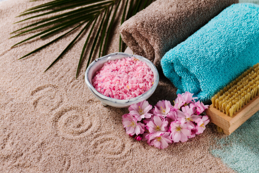 Spa Concept. Closeup of beautiful Spa Products - Spa Salt, Towels and Flowers. Horizontal.
