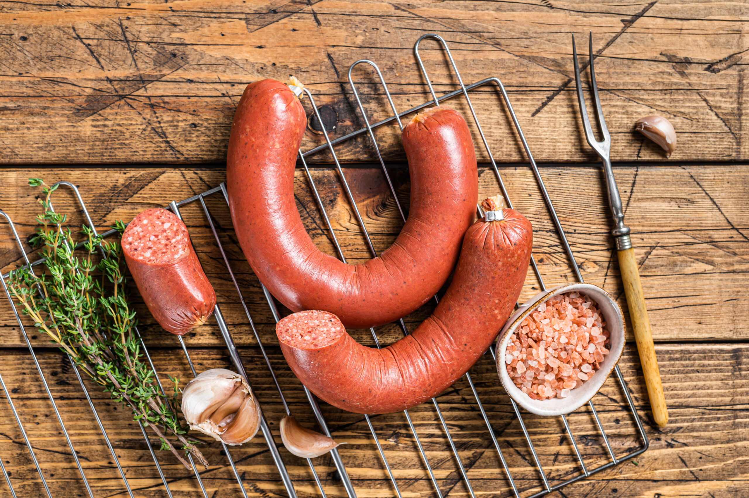 Turkish Sucuk beef meat sausage on a grill. Wooden background. Top view.